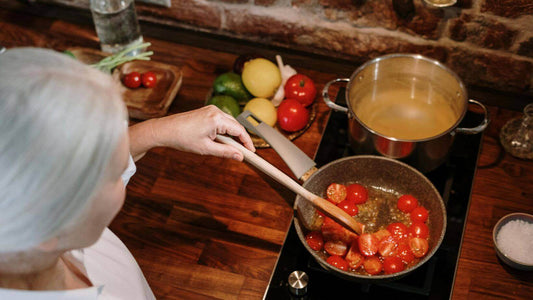 woman stirring a pot of simmering tomatoes on a stovetop