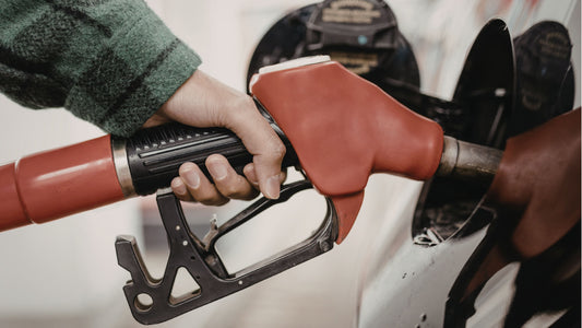Hand holding red fuel pump to fill up car