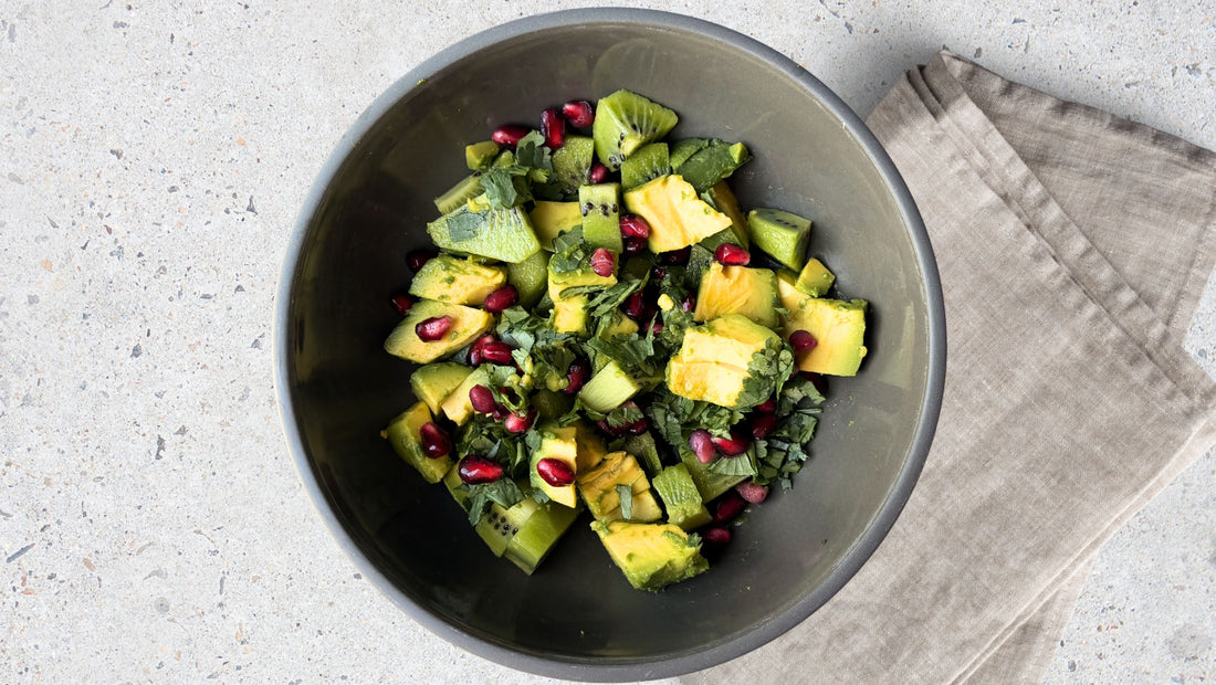 Fresh, seasonal, organic kiwi fruit, avocado, pomegranate, jalepeno and coriander salsa on white kitchen bench