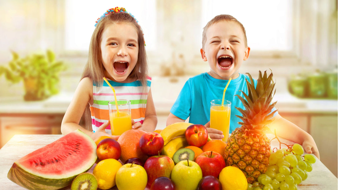 Two smiling children enjoying healthy fruit snacks including watermelon, pineapple, grapes and apples at the kitchen table during the school holidays.