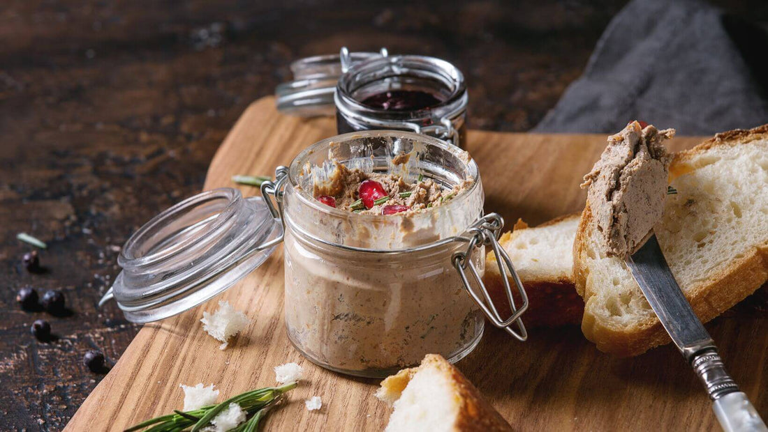 Jars of pate on a wooden board with bread slices and a knife.