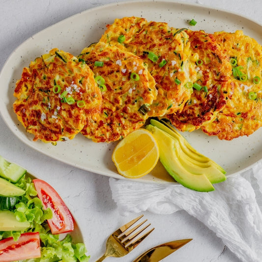 Platter of vegetable fritters with avocado and lemon on a white background