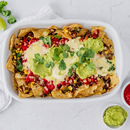 Baked nachos with sour cream, and cilantro on a white plate.