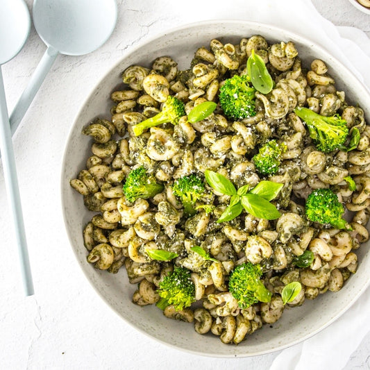 Pasta with broccoli and pesto in a white bowl on a light background