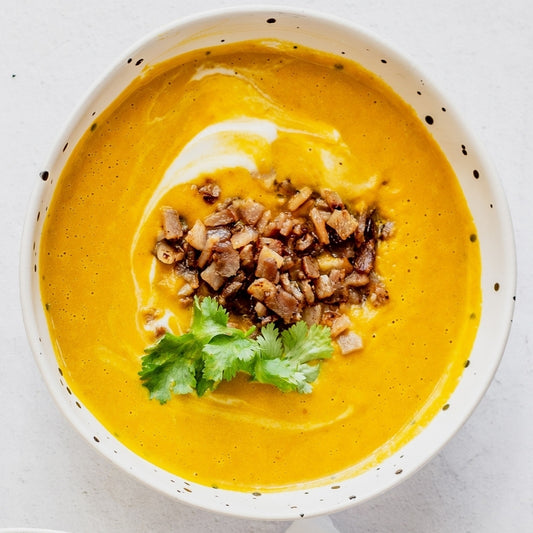 Pumpkin soup in a white bowl with garnishes on a light background
