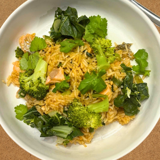 Plate of rice with broccoli and greens on a brown surface
