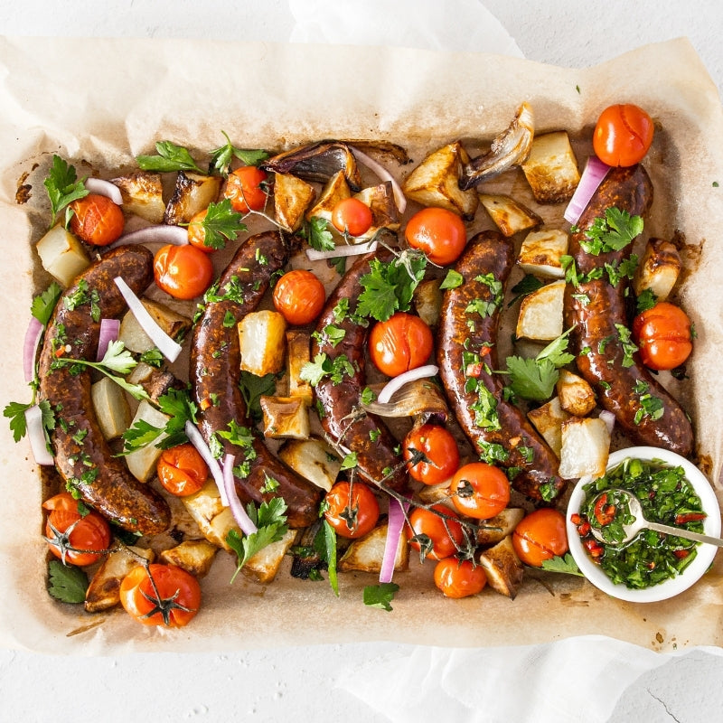 Roasted sausages with vegetables on a baking tray