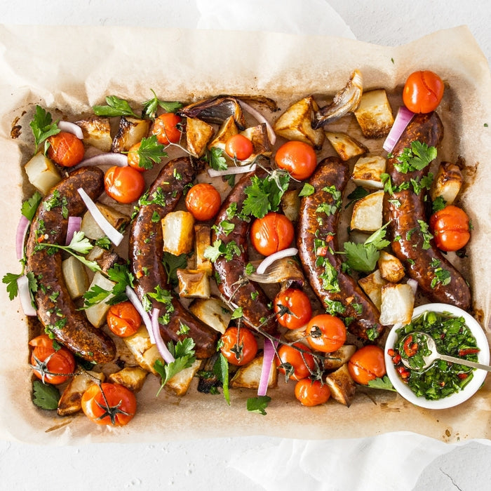 Roasted sausages with vegetables on a baking tray