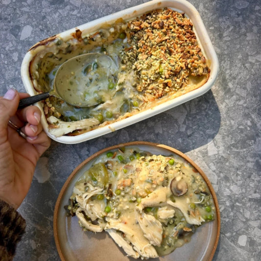 Baked dish with a scoop taken out, showing a creamy mixture and crumbly topping on a gray surface.